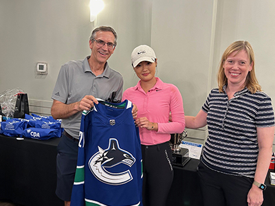 Brad Martyniuk from Lindsay Kenney LLP and CPABC President & CEO Lori Mathison present Ladies’ Closest to the Pin winner, Stella Hew